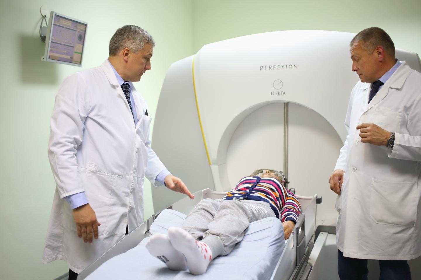 двое врачей помещают девушку в аппарат для лечения
