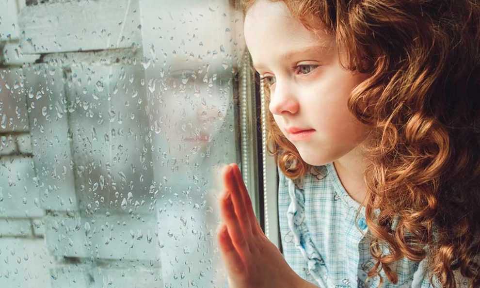 Девочка смотрит в окно, капли дождя