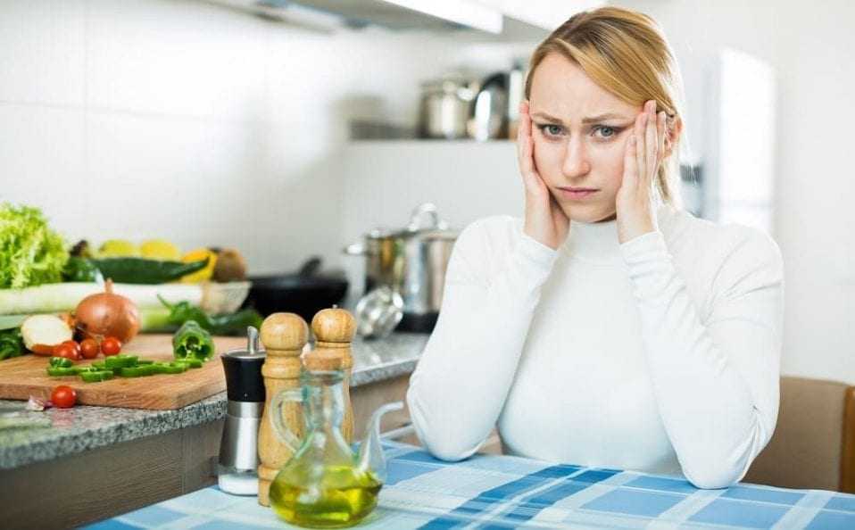 Женщина в кухне с мигренью