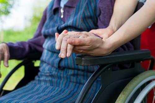Инвалида с болезнью Паркинсона держат за руку