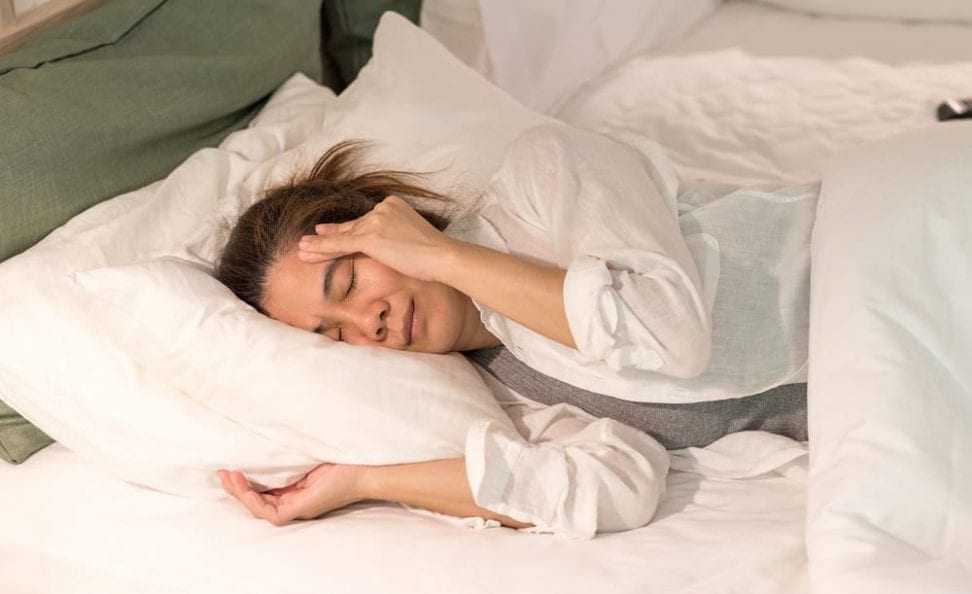 Жещина в постели с утренним приступом мигрени