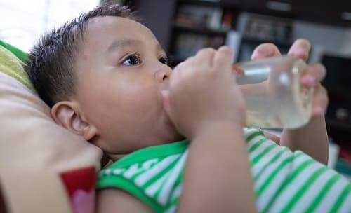 Ребенок сосредоточен на бутылочке с водой